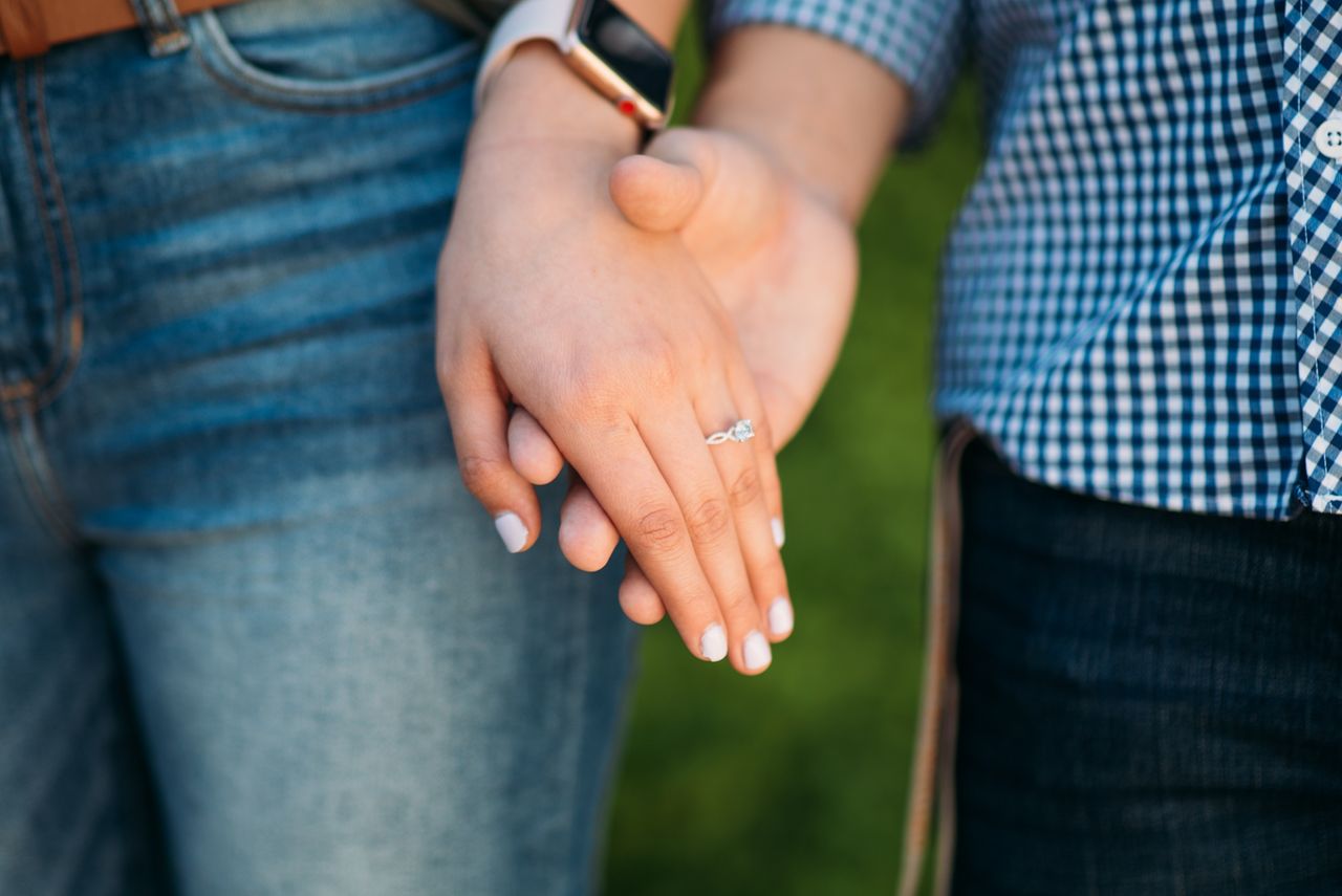 Casually dressed engaged couple featuring a gorgeous engagement ring