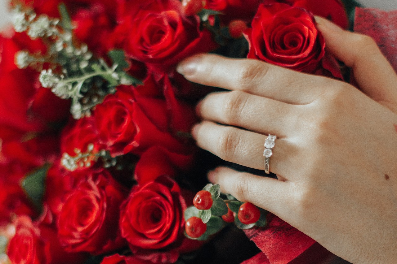 A fashionable married woman’s hand holding a bouquet of roses