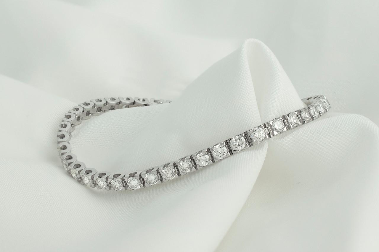  A silver diamond tennis bracelet lying on a white cloth