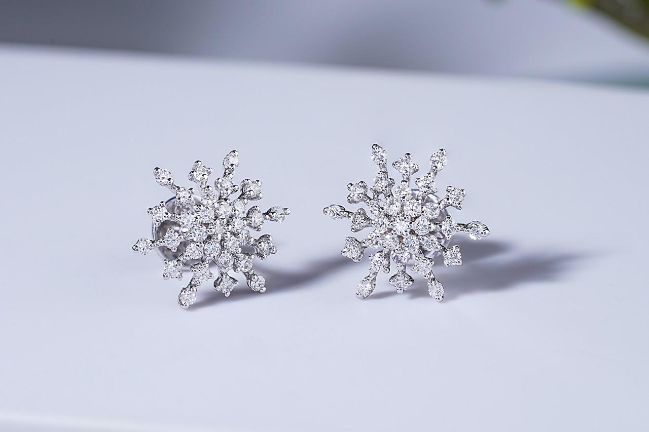 A pair of diamond earrings, featuring gems arranged in an elaborate floral pattern