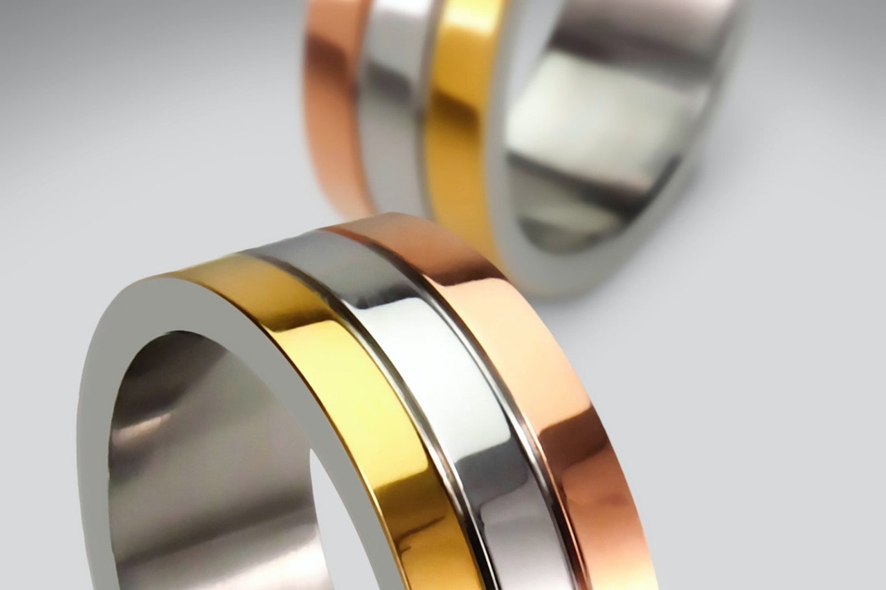Close-up image of two matching rings that feature three bands of various metal types