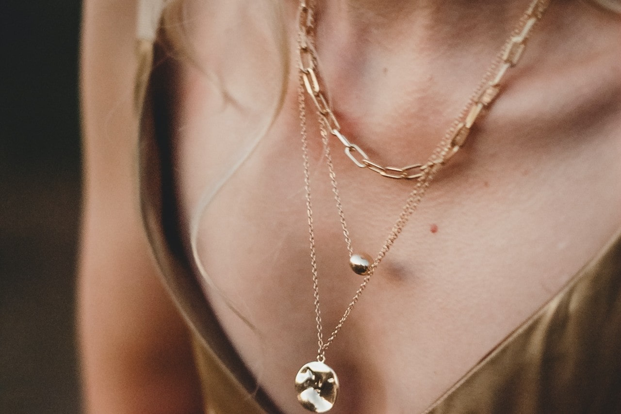 A woman’s neck wearing three necklaces of varying lengths