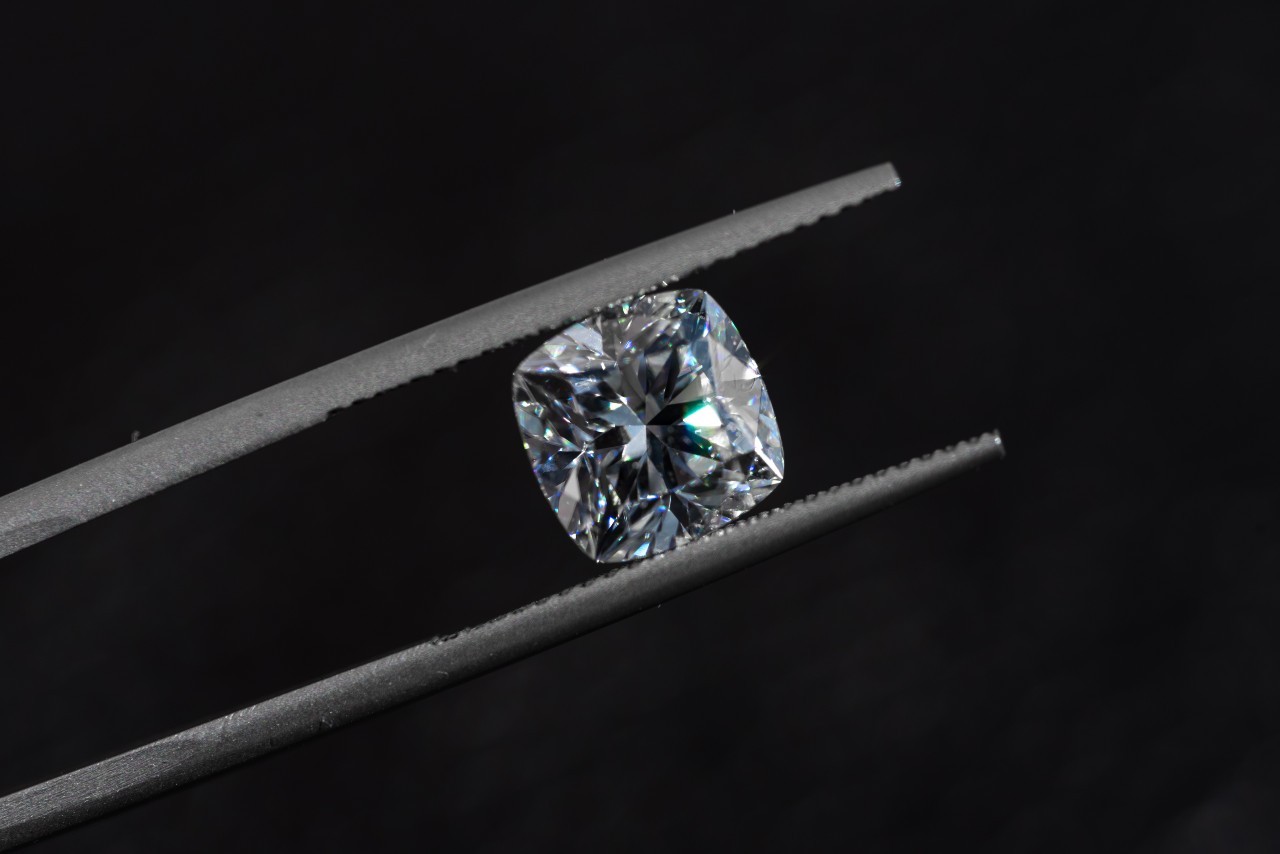 cushion cut diamond being held by jeweller's tweezers