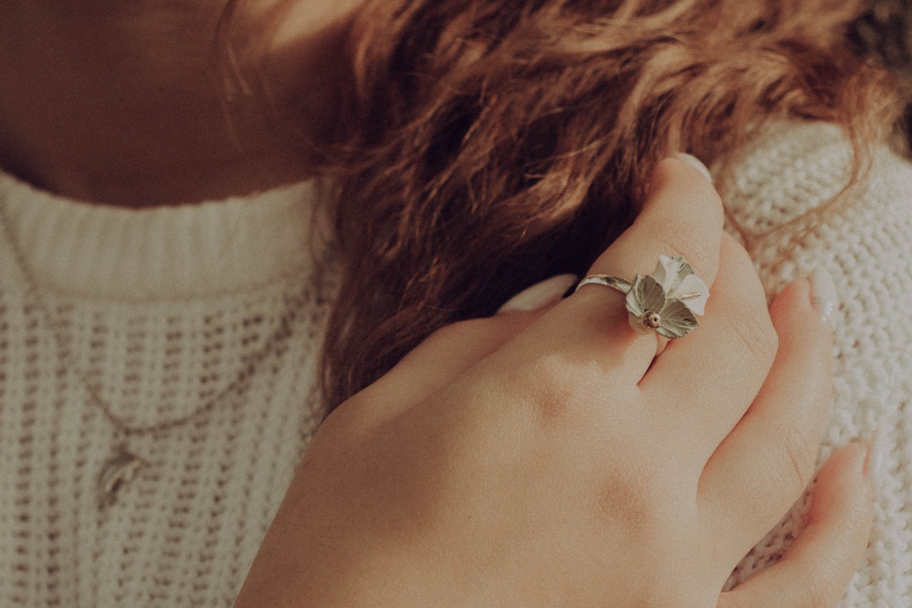 A woman wearing a fashion ring touches her curly hair