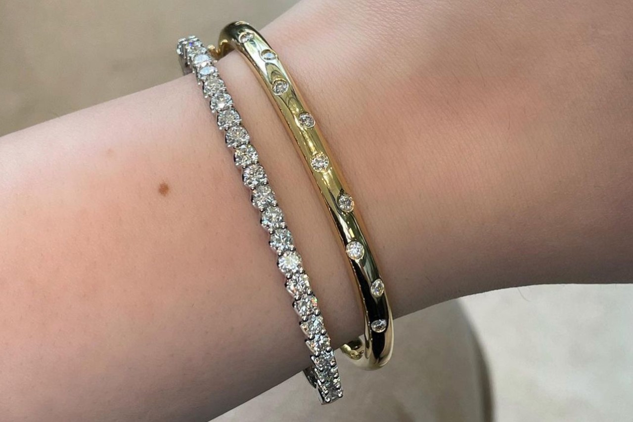 two bangles: one white gold covered in diamonds, the other yellow gold with bezel set diamonds