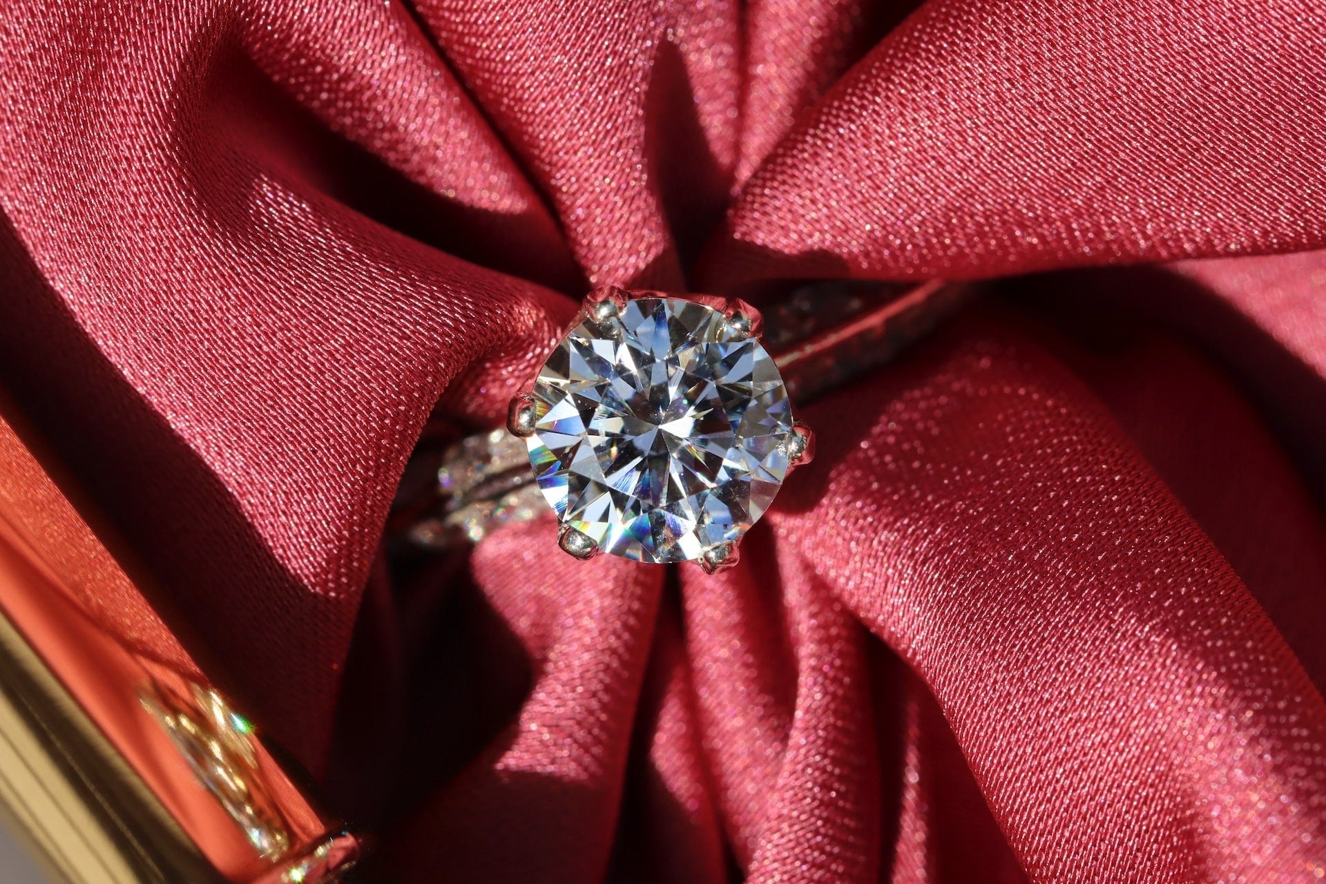 a sparkling diamond ring on a red fabric background