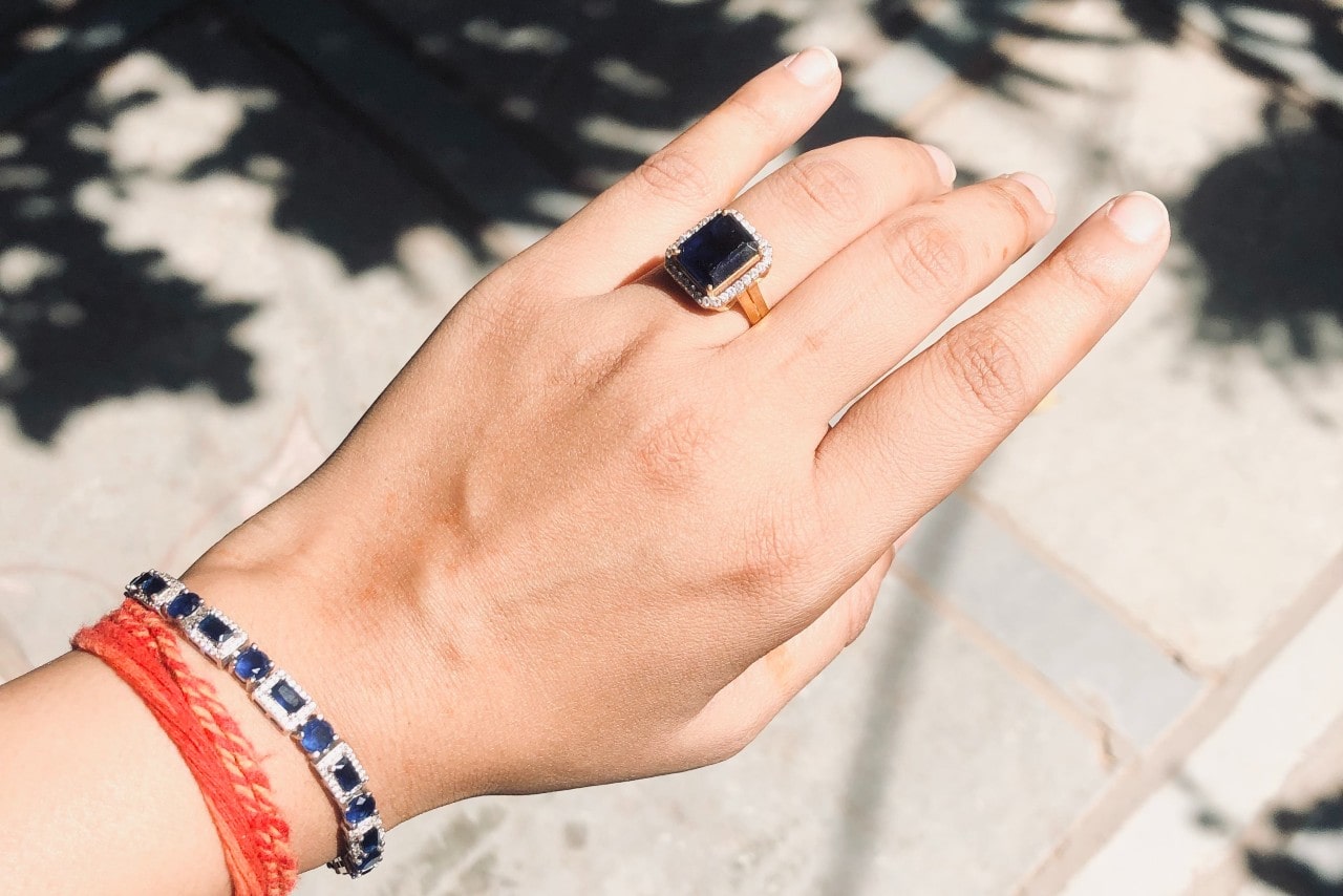 A woman wearing a diamond and sapphire bracelet along with a matching statement ring