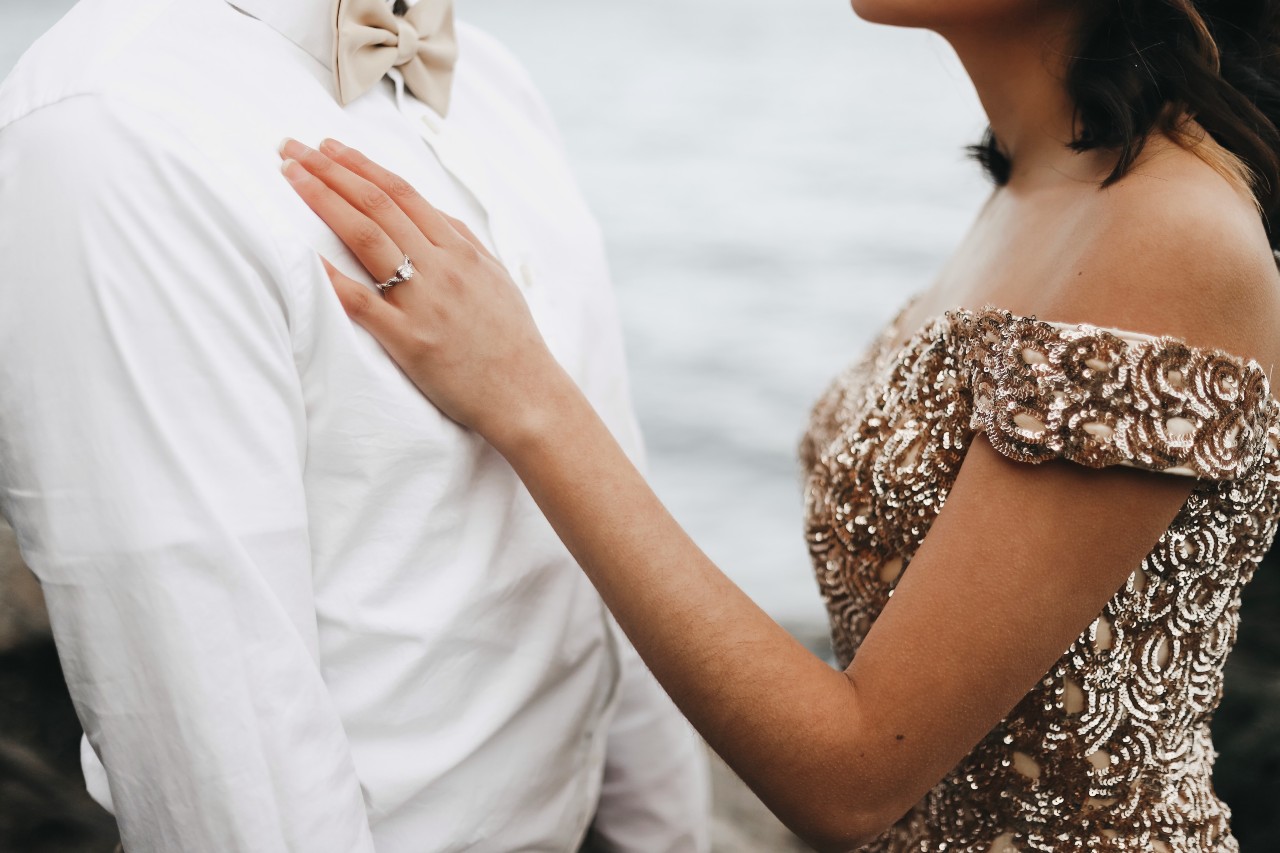 A bride and groom at an outdoor wedding near water.