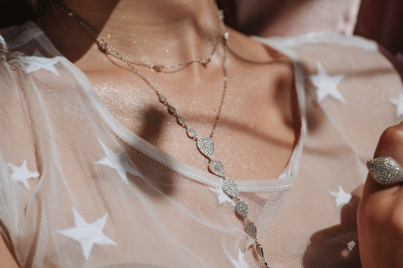 close up image of a woman’s neckline, wearing silver necklaces and a star print shirt