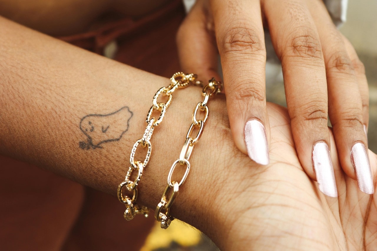 A close-up of a woman’s wrist adorned with a gold bracelet.