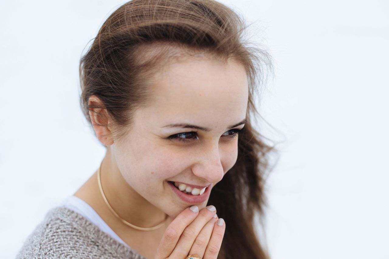 gold necklace on woman smiling looking to side