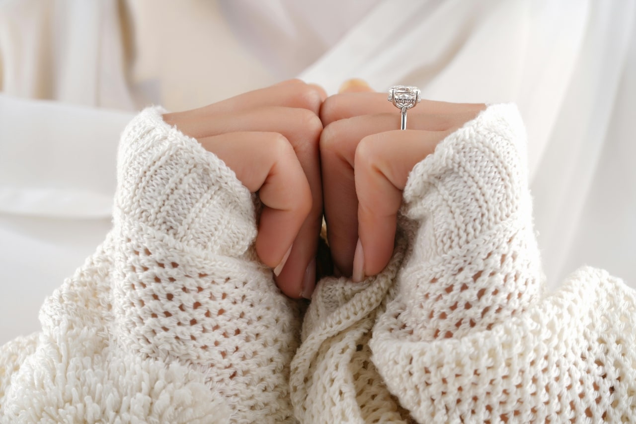 Side view of a hidden halo white gold ring while wearing a white sweater